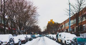 district 7: snow in the street with cars lining it and snow on top