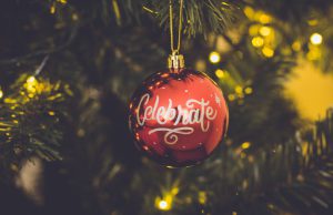 holiday: red ornament that says celebrate hanging on a tree