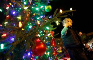 christmas tree with colorful lights and a young boy looking at it