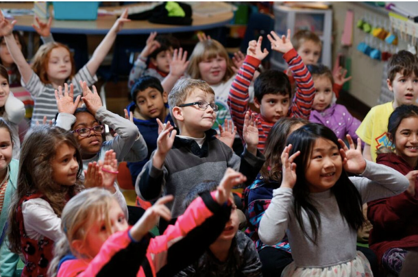 group of elementary kids raising their hands