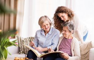 senior: A teenage girl, her mother and grandmother looking at old photographs at home. Family and generations concept.