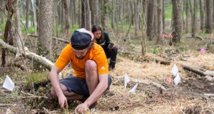 environmental: a man in an orange shirt and hat digging in the ground