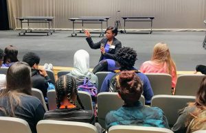 Citizens Youth Academy: woman in a purple dress with black cardigan talking to a group of students