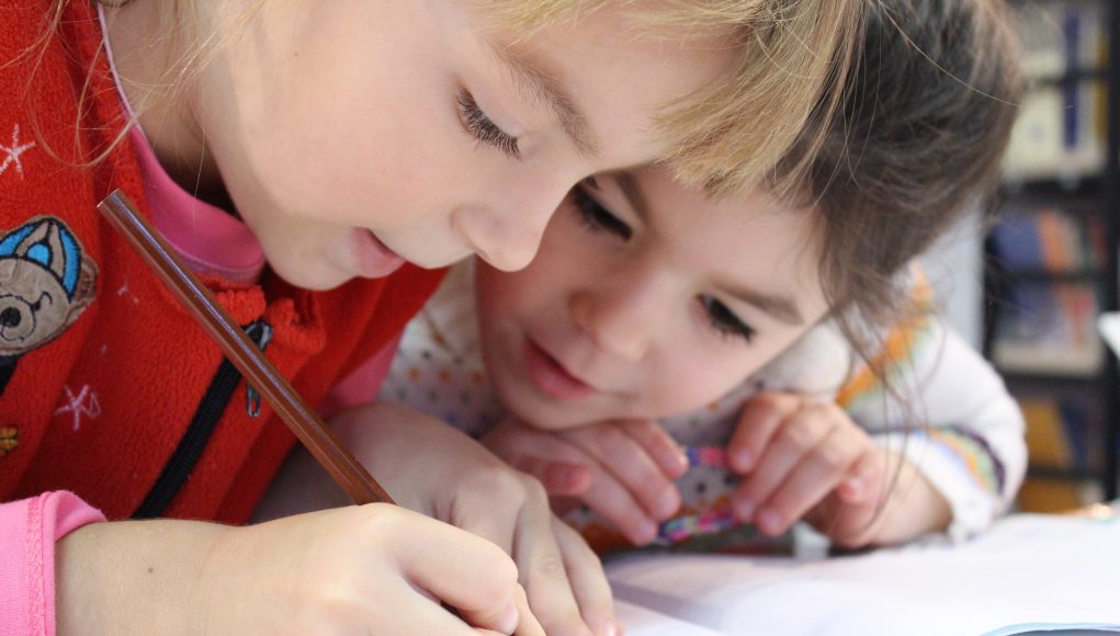 harmony day montessori school: two kids drawing on a sheet with a colored pencil