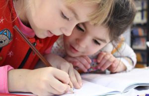 harmony day montessori school: two kids drawing on a sheet with a colored pencil
