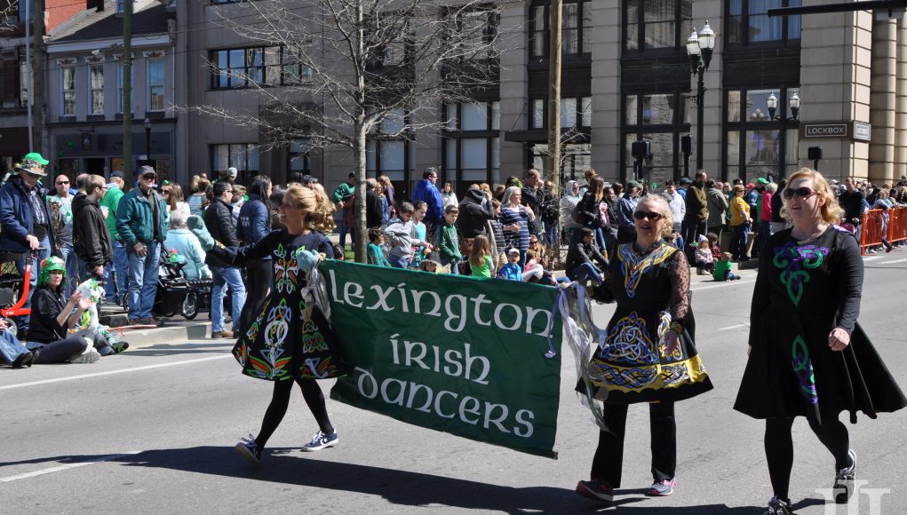 Parade: group of 3 women wearing traditional irish dancing garb holding a banner