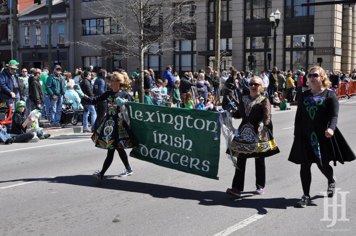 Parade: group of 3 women wearing traditional irish dancing garb holding a banner