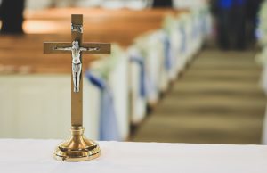 Easter Service: wooden cross on a table with a white cloth and pews