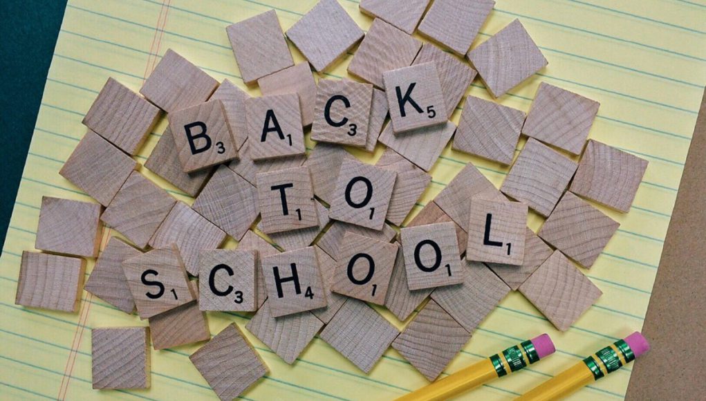 KIds: back to school with scrabble letters on yellow paper and two pencils