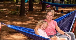Neighborhood: a mother and daughter sitting in a hammock surrounded by trees