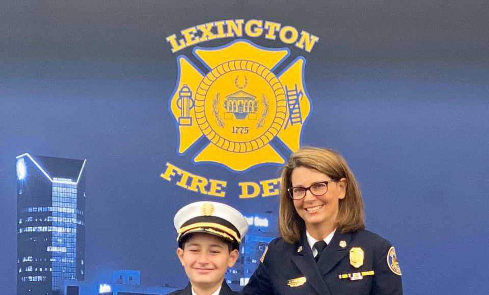 Family: a young boy and older woman dressed in fire chief uniforms