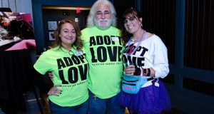 Pet: group of people wearing lime green shirt that says adopt love and a girl dressed from the 80's