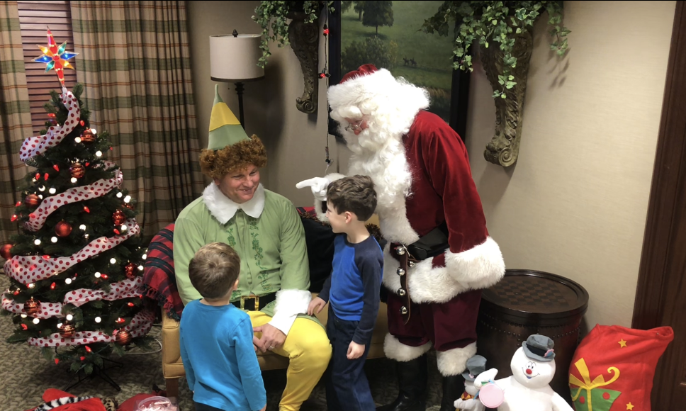 family holiday guide Neighborhood: a man dressed as elf and santa claus with kids
