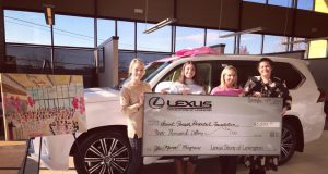 neighborhood: group of girls holding a giant check with a car behind them